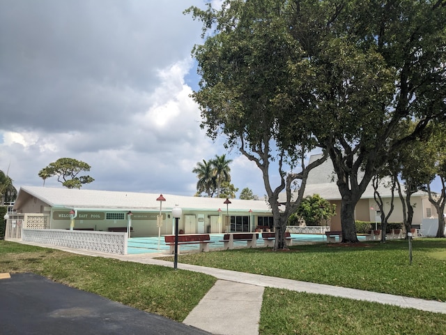 view of front facade featuring a community pool and a front lawn