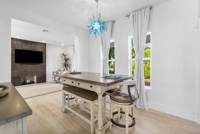 dining area with a tile fireplace and light hardwood / wood-style floors