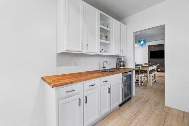 kitchen featuring butcher block counters, white cabinets, hanging light fixtures, and wine cooler