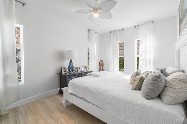 bedroom with ceiling fan, light hardwood / wood-style floors, and multiple windows