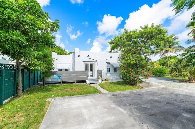 back of house featuring a lawn and a wooden deck