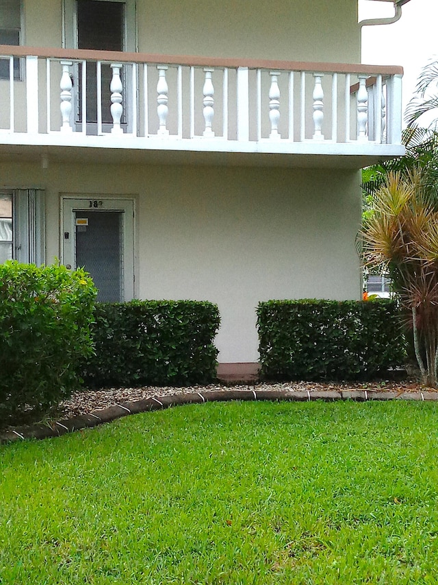 view of side of home with a balcony and a yard