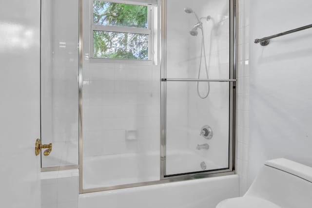 bathroom featuring combined bath / shower with glass door and toilet