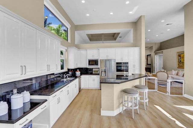 kitchen featuring white cabinets, decorative backsplash, a kitchen bar, and stainless steel appliances