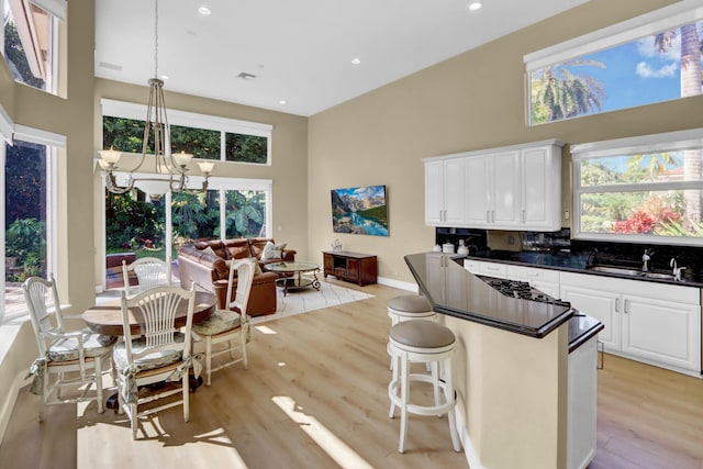 kitchen with white cabinetry, sink, a chandelier, decorative light fixtures, and light hardwood / wood-style floors