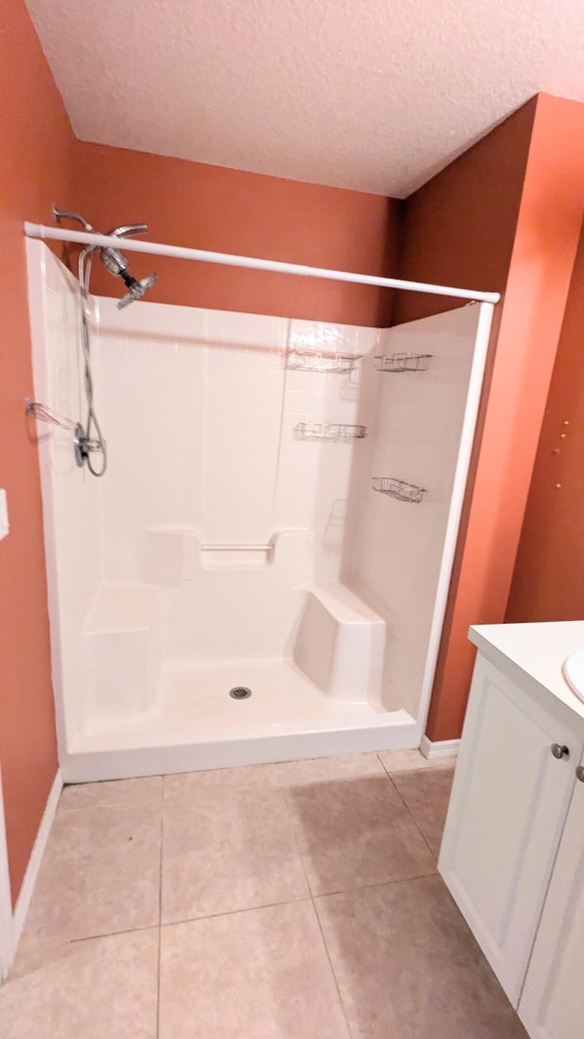 bathroom featuring a textured ceiling, a shower, tile patterned flooring, and vanity