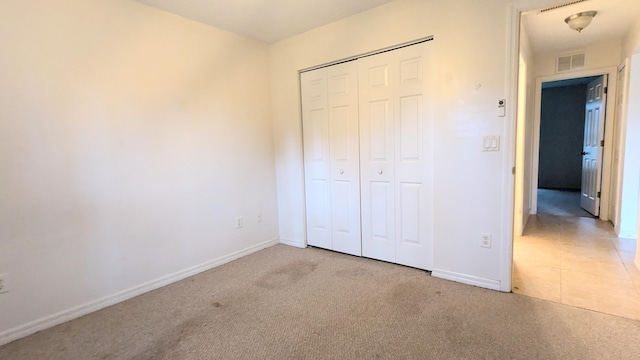 unfurnished bedroom with light colored carpet and a closet