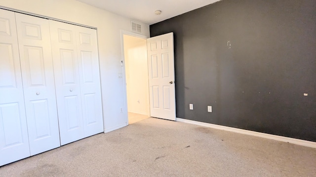 unfurnished bedroom with light carpet and a closet