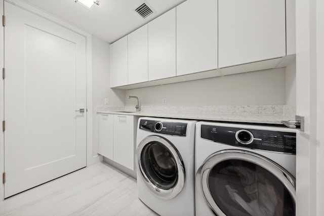 laundry area with washing machine and dryer, cabinets, and sink