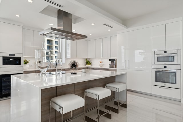 kitchen featuring a spacious island, white cabinets, a kitchen bar, and island range hood