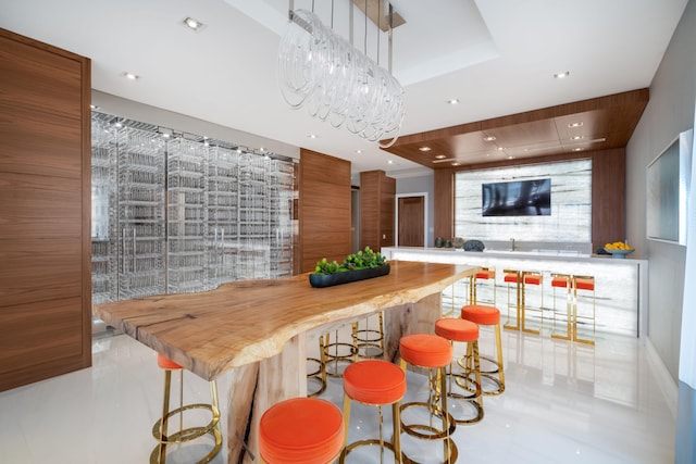 bar with wooden counters, a tray ceiling, and light tile patterned floors