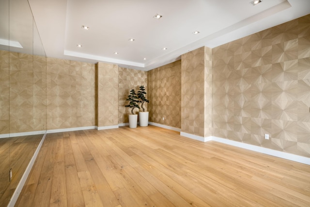 unfurnished room featuring a tray ceiling and hardwood / wood-style floors