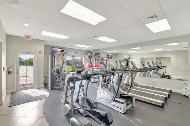 workout area with a paneled ceiling and light tile patterned flooring