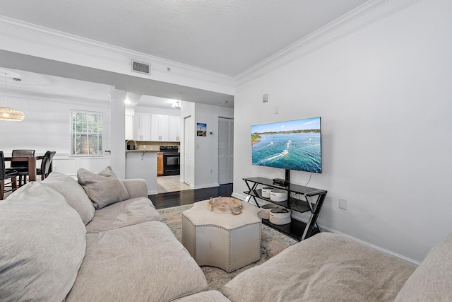 living room featuring ornamental molding, hardwood / wood-style floors, an inviting chandelier, and a textured ceiling