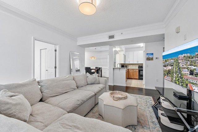 living room with ornamental molding, a textured ceiling, and light hardwood / wood-style floors