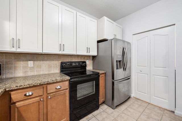 kitchen featuring light stone countertops, black / electric stove, white cabinetry, light tile patterned floors, and stainless steel refrigerator with ice dispenser