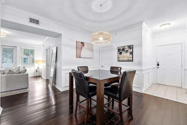 dining room featuring wood-type flooring, ornamental molding, and an inviting chandelier