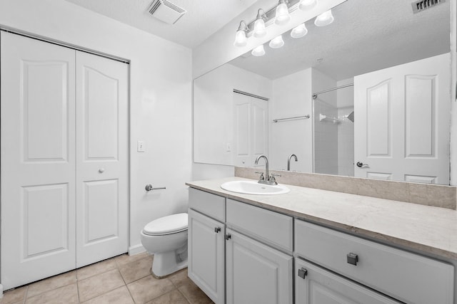 bathroom featuring vanity, walk in shower, tile patterned floors, toilet, and a textured ceiling