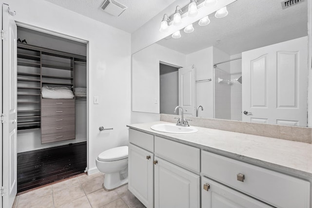 bathroom featuring vanity, wood-type flooring, toilet, a shower, and a textured ceiling