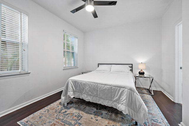 bedroom featuring ceiling fan, dark wood-type flooring, and multiple windows