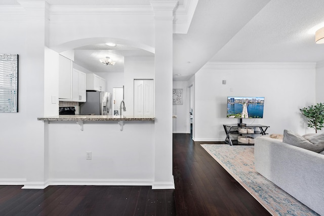 kitchen with a kitchen breakfast bar, dark wood-type flooring, kitchen peninsula, stainless steel fridge with ice dispenser, and white cabinetry