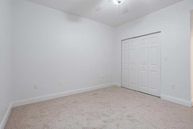 unfurnished bedroom featuring light colored carpet, a closet, and ceiling fan