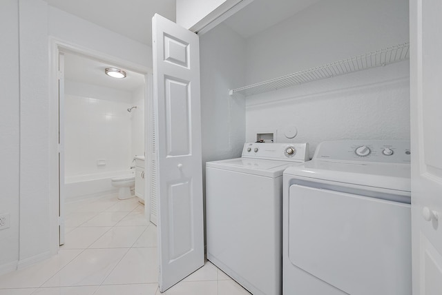 clothes washing area featuring washing machine and dryer and light tile patterned floors