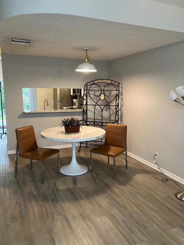 dining space with wood-type flooring and a textured ceiling