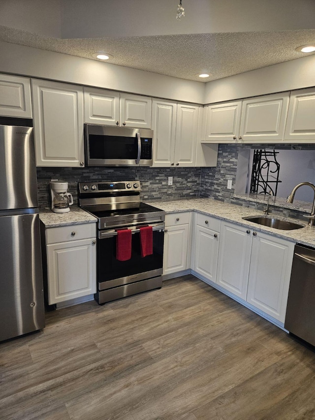 kitchen with wood-type flooring, white cabinetry, sink, and appliances with stainless steel finishes