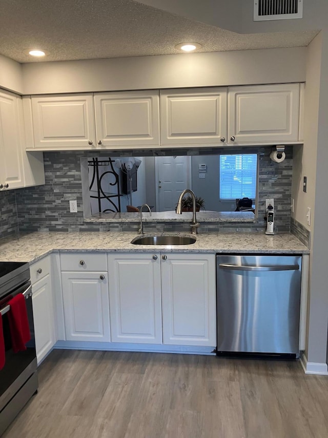 kitchen featuring appliances with stainless steel finishes, light hardwood / wood-style flooring, white cabinetry, and sink