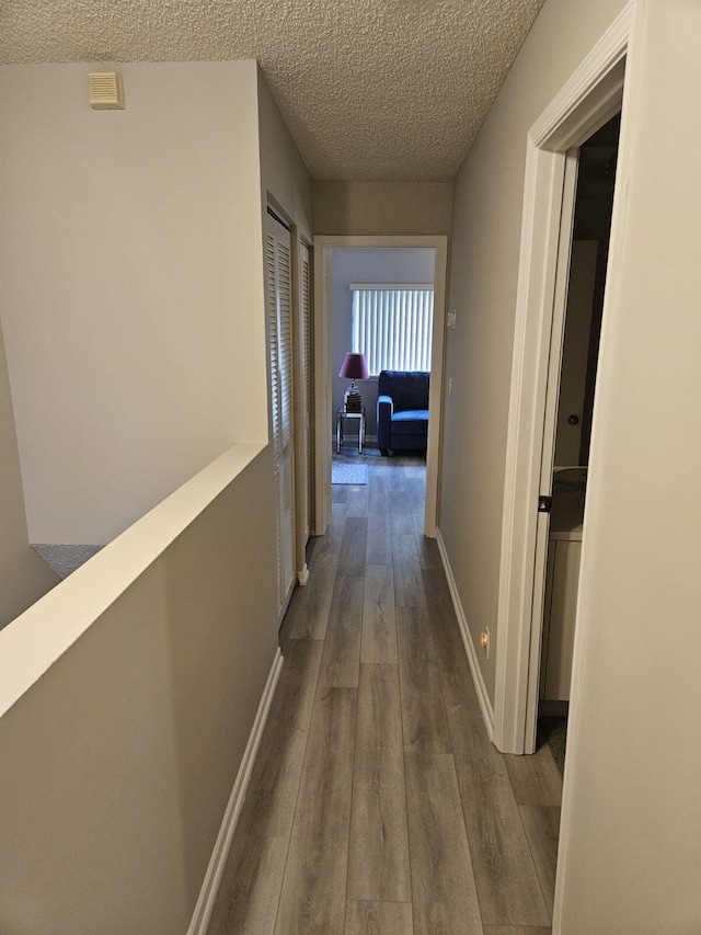 corridor featuring hardwood / wood-style floors and a textured ceiling