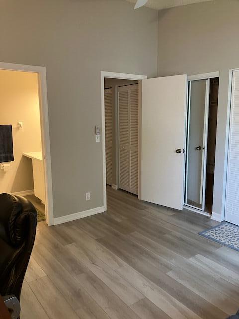 unfurnished bedroom with light wood-type flooring and high vaulted ceiling