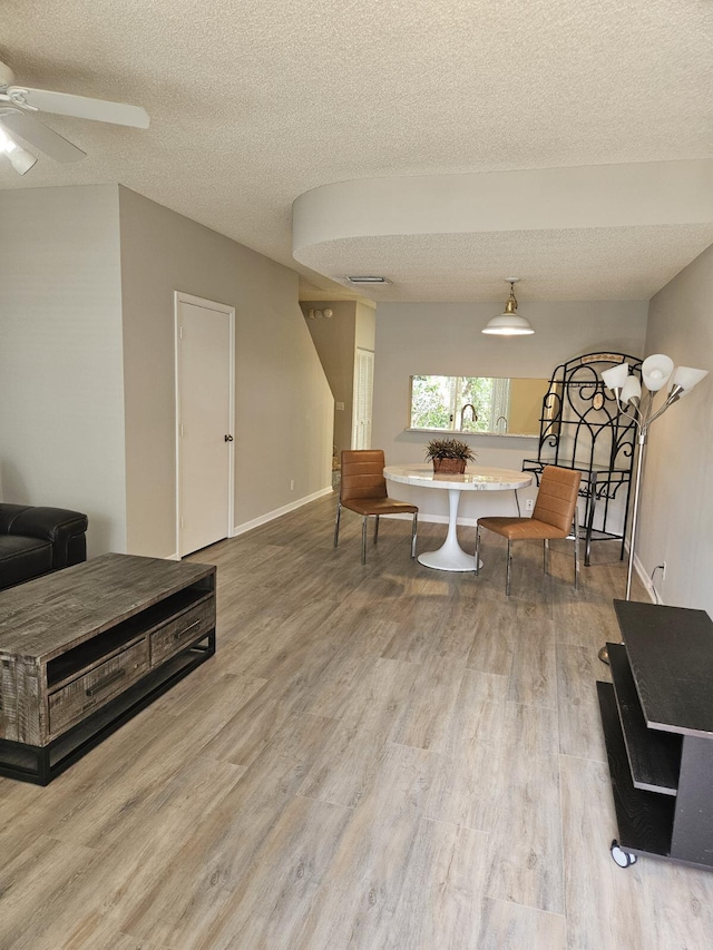 dining area with ceiling fan, wood-type flooring, and a textured ceiling