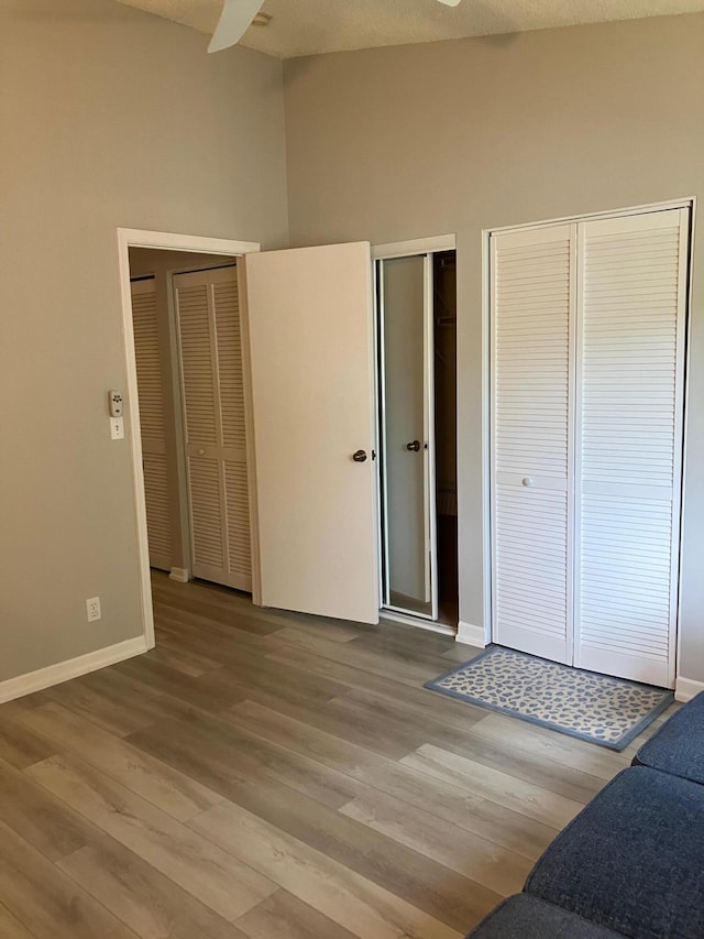 bedroom with a textured ceiling, ceiling fan, two closets, and light wood-type flooring