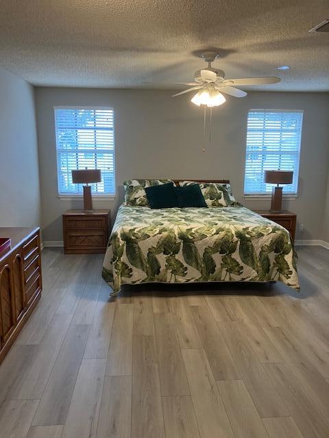 bedroom featuring ceiling fan, light hardwood / wood-style floors, and a textured ceiling