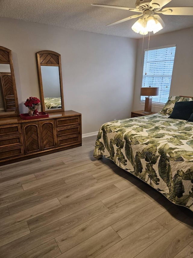 bedroom featuring a textured ceiling, light wood-type flooring, and ceiling fan