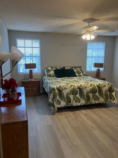 bedroom featuring a textured ceiling, light wood-type flooring, and ceiling fan