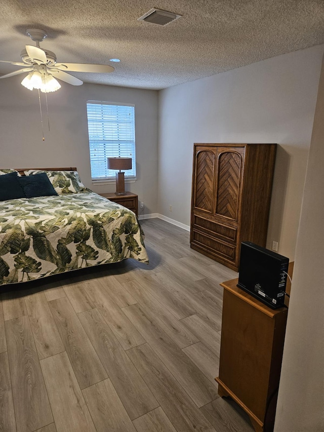 bedroom featuring ceiling fan, wood-type flooring, and a textured ceiling