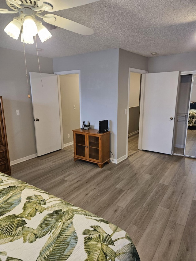 bedroom featuring ceiling fan, wood-type flooring, and a textured ceiling