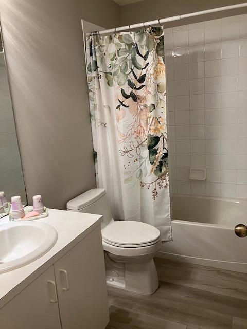 full bathroom featuring hardwood / wood-style floors, vanity, toilet, and shower / bath combo with shower curtain