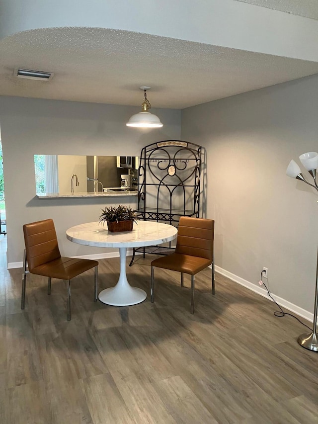 dining space featuring wood-type flooring and a textured ceiling