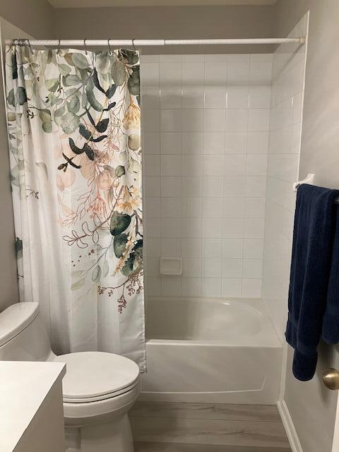 full bathroom featuring hardwood / wood-style floors, shower / bath combination with curtain, toilet, and vanity