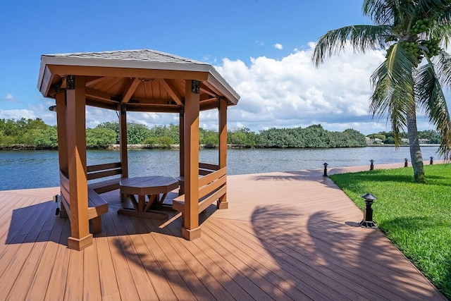 dock area with a gazebo, a water view, and a lawn