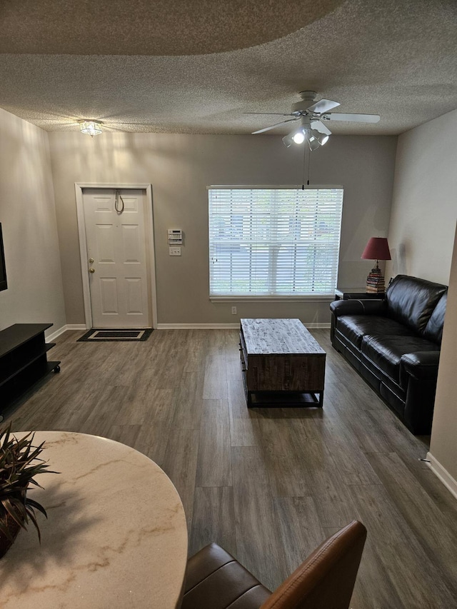 living room with ceiling fan, dark hardwood / wood-style flooring, and a textured ceiling