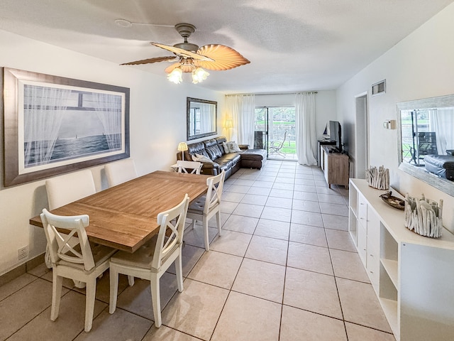 tiled dining room featuring ceiling fan, lofted ceiling, and a textured ceiling