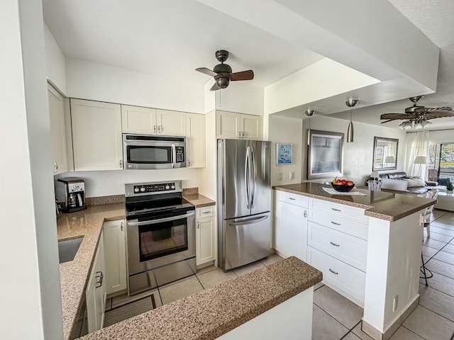 kitchen with stainless steel appliances, open floor plan, ceiling fan, and a peninsula