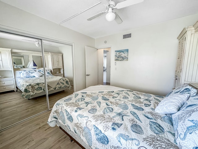 bedroom with ceiling fan, a closet, visible vents, and wood finished floors