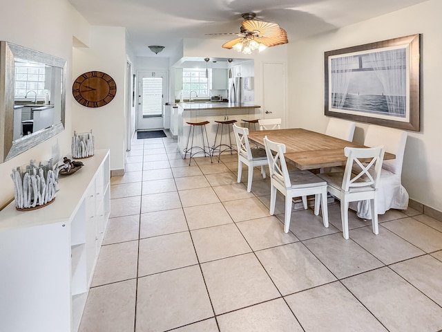 tiled dining area featuring ceiling fan and sink