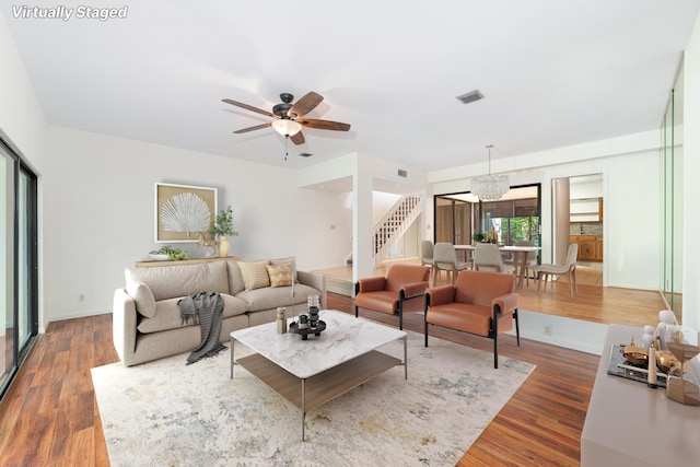 living room with dark wood-type flooring and ceiling fan with notable chandelier