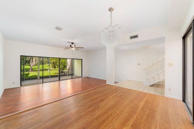 empty room featuring ceiling fan with notable chandelier and light hardwood / wood-style flooring